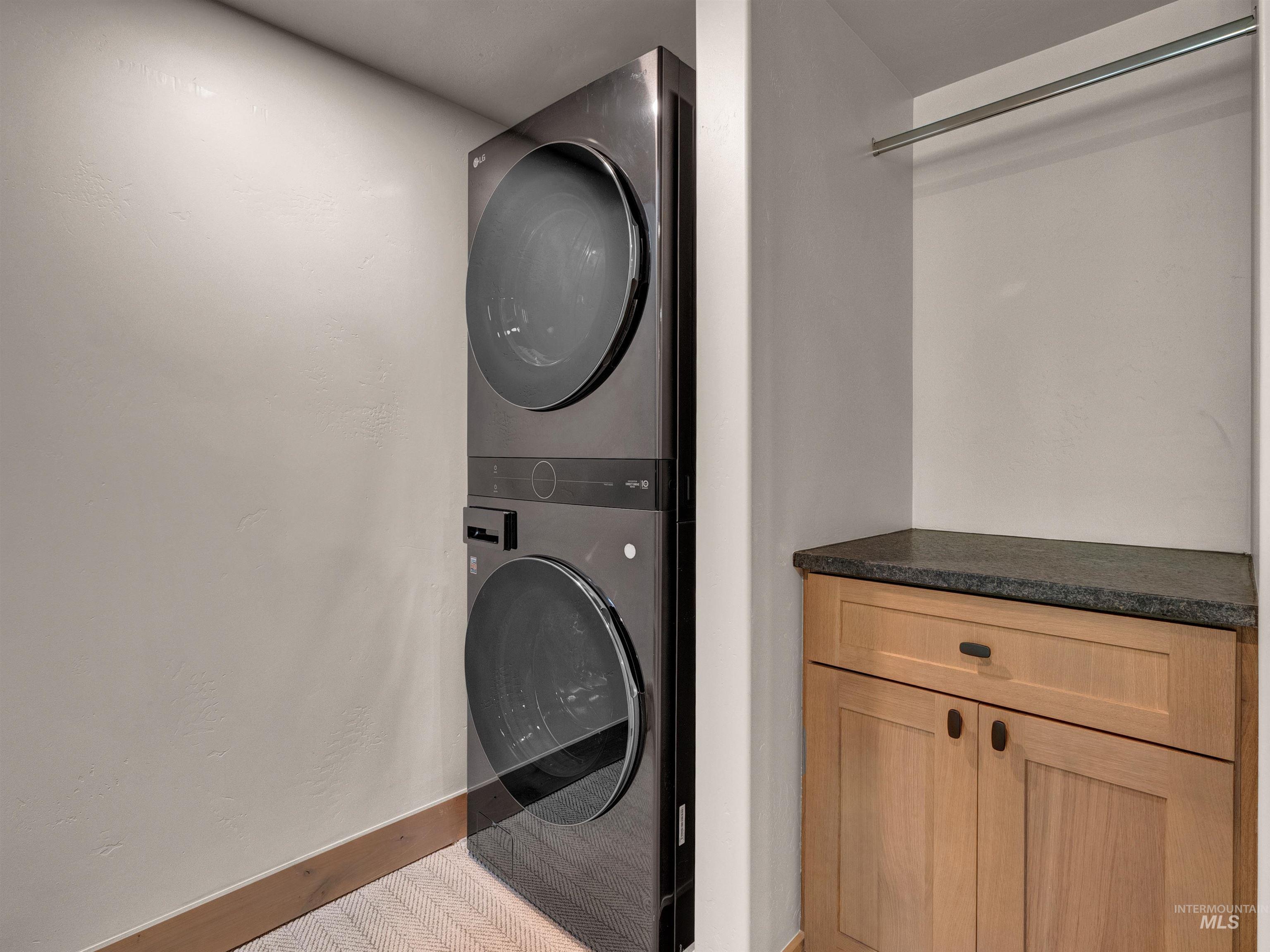 Laundry area with stacked washer / dryer and baseboards