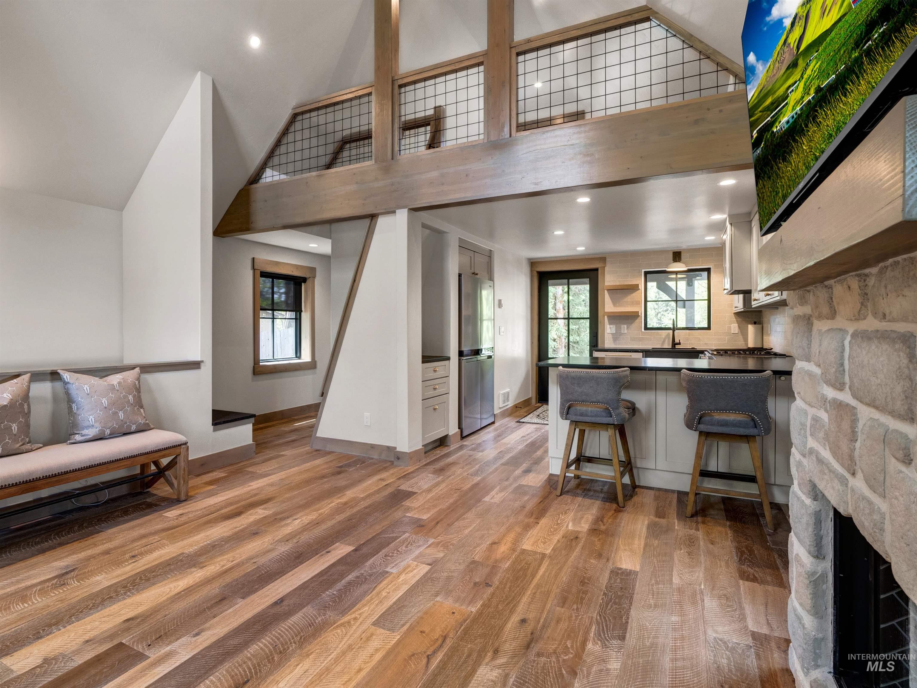 Kitchen with open shelves, a peninsula, a kitchen breakfast bar, light wood finished floors, and dark countertops