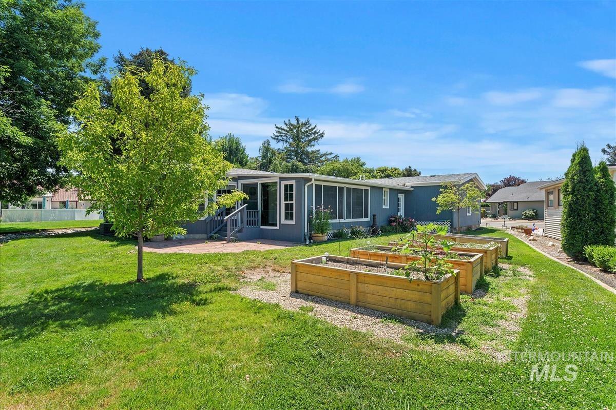 Back of house with a garden, a sunroom, a lawn, entry steps, and a patio