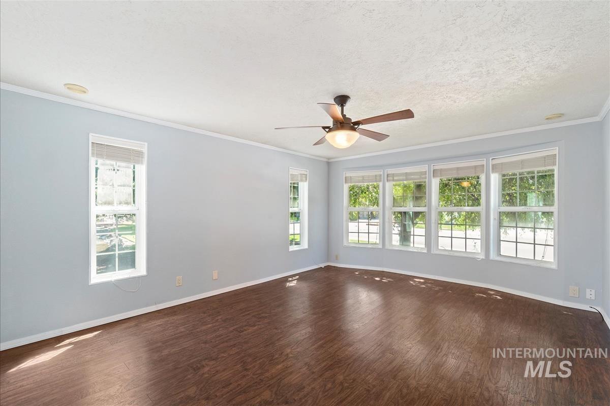 Spare room featuring wood finished floors, healthy amount of natural light, crown molding, a ceiling fan, and a smoke detector