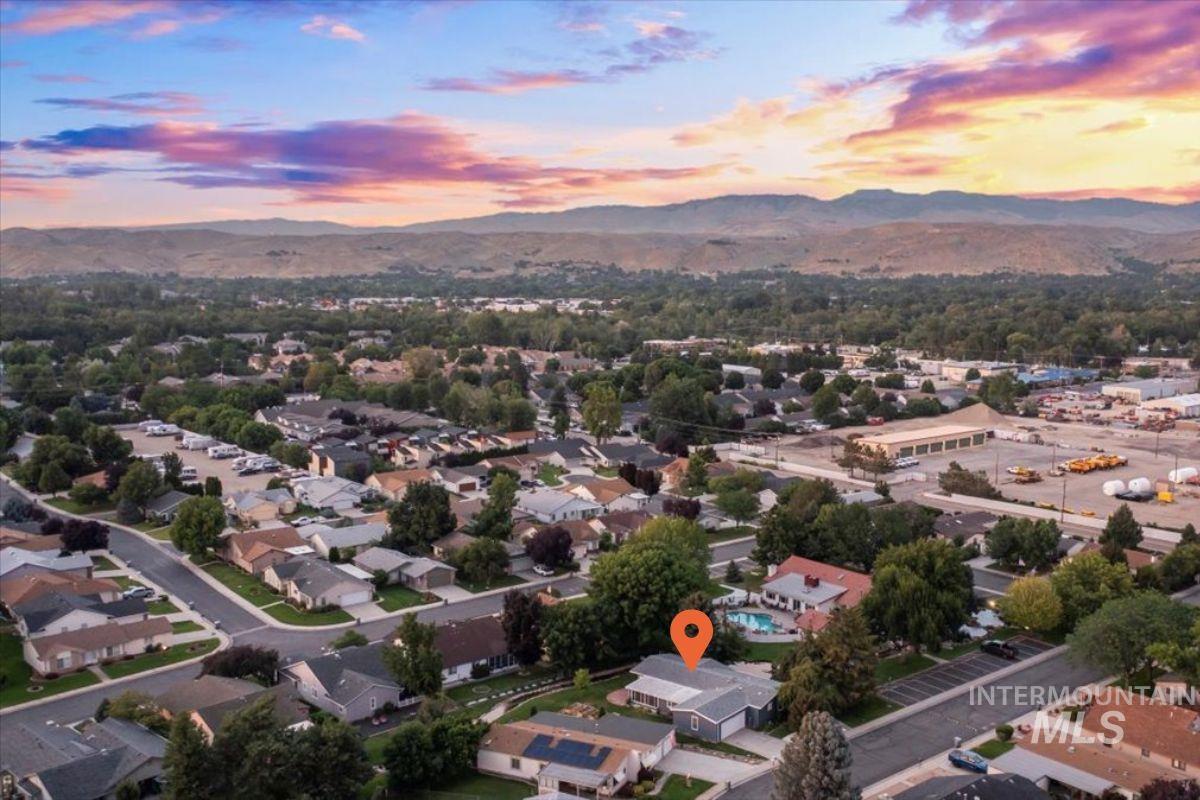 Aerial view of property and surrounding area with a mountain backdrop and nearby suburban area