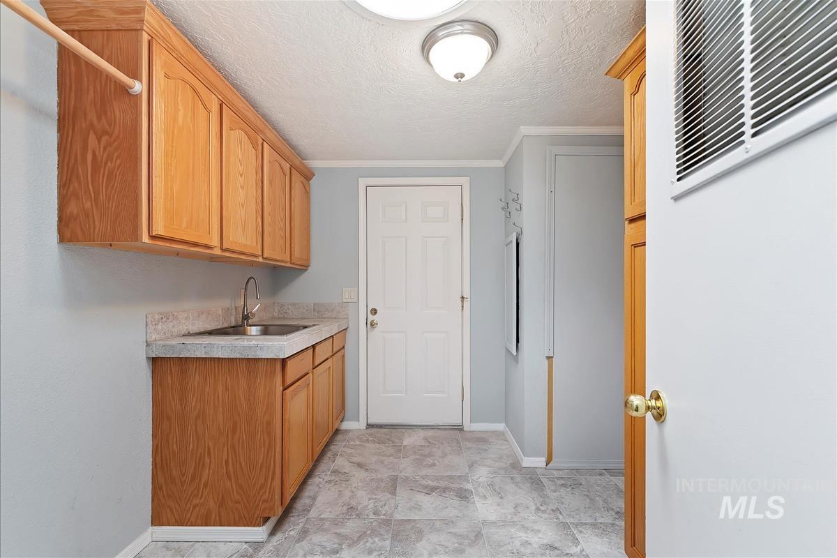 Laundry area with crown molding and a textured ceiling