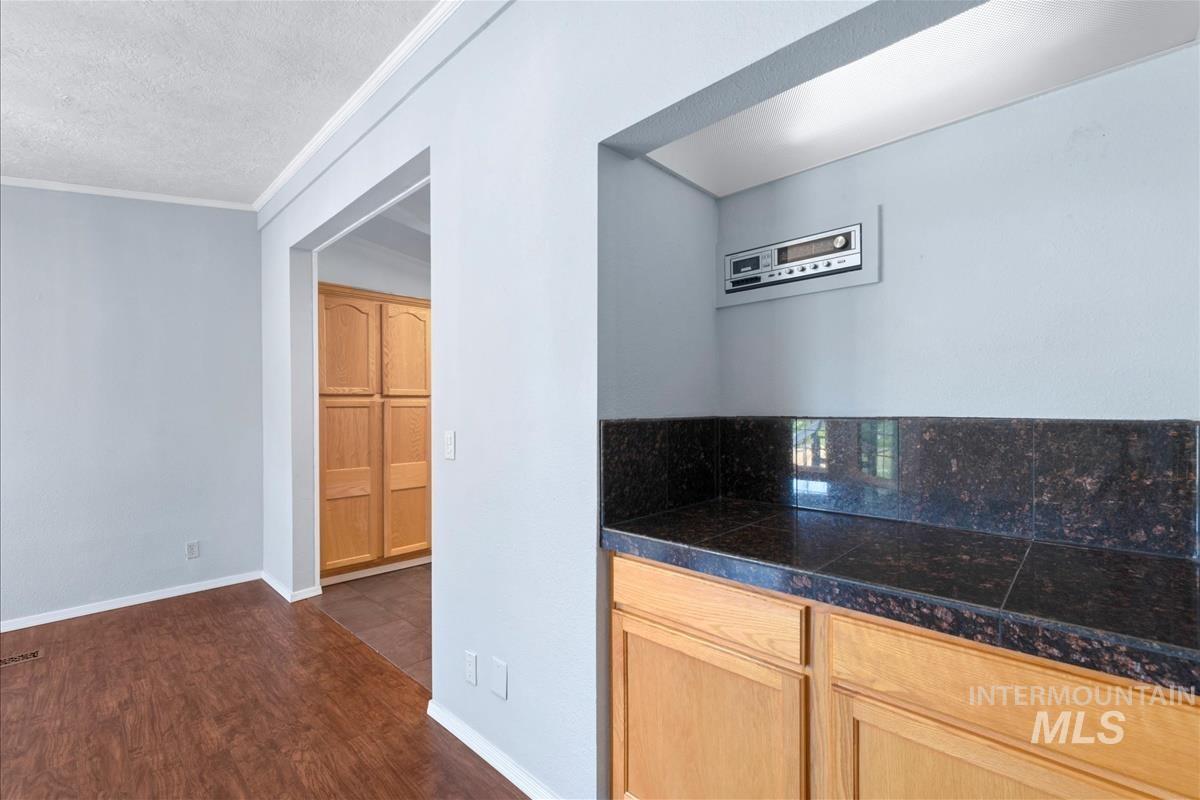 Kitchen with tile countertops, dark wood-style floors, a textured ceiling, and crown molding