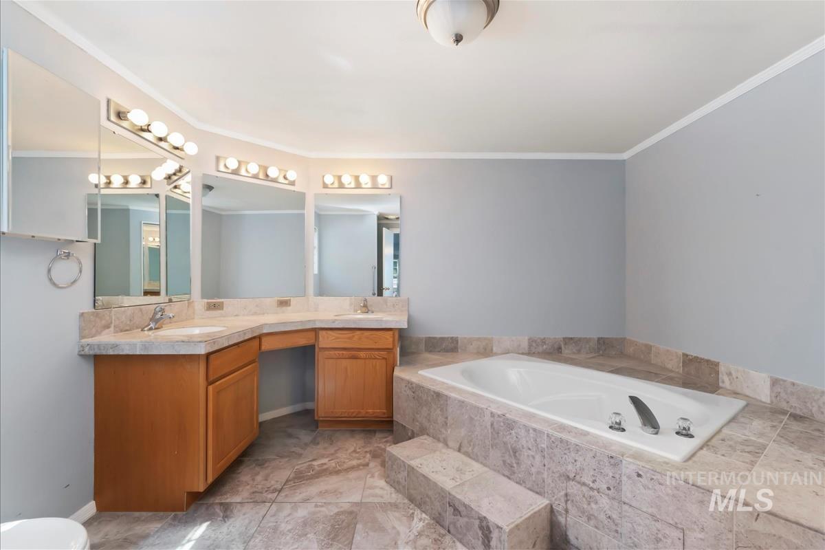 Bathroom with a garden tub, double vanity, and crown molding