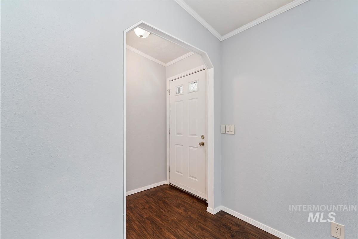 Hall with dark wood finished floors and ornamental molding