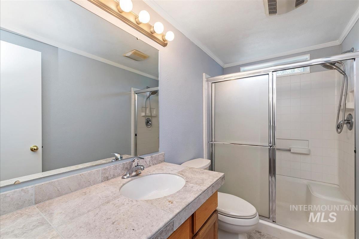 Full bath with vanity, a stall shower, and crown molding