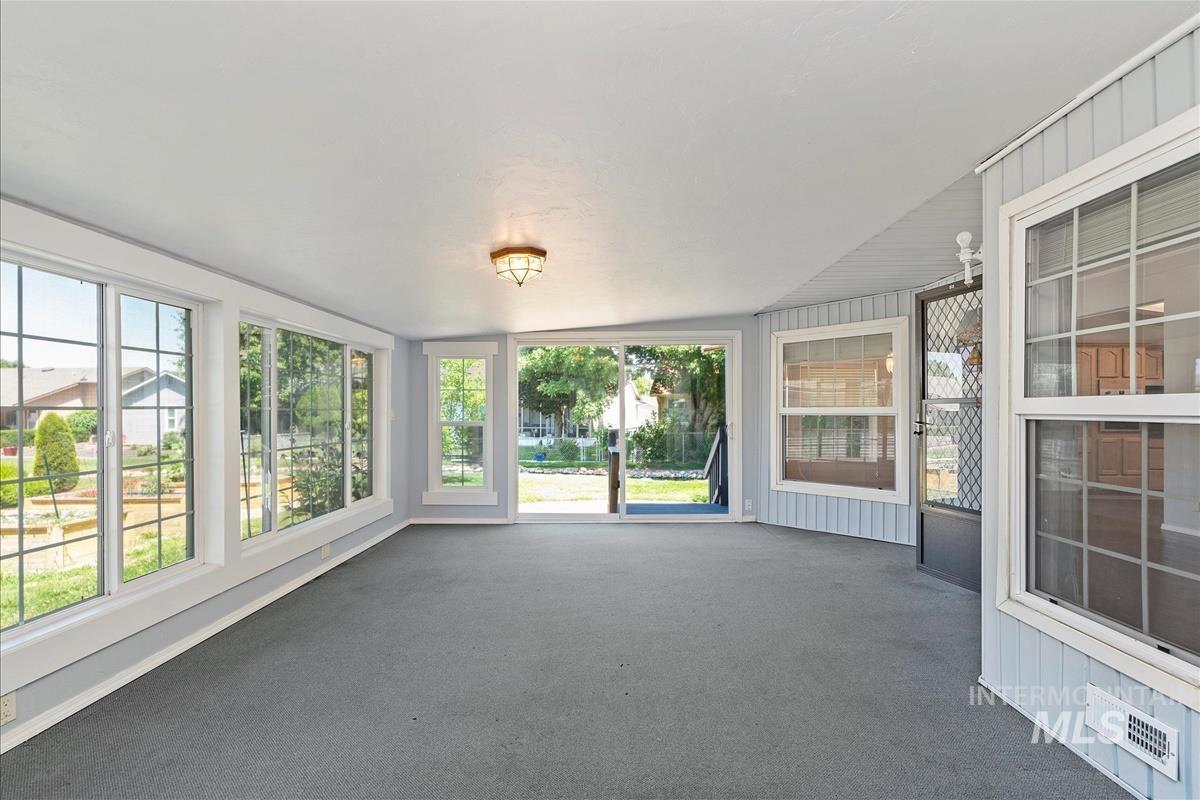 Unfurnished sunroom with plenty of natural light and carpet floors