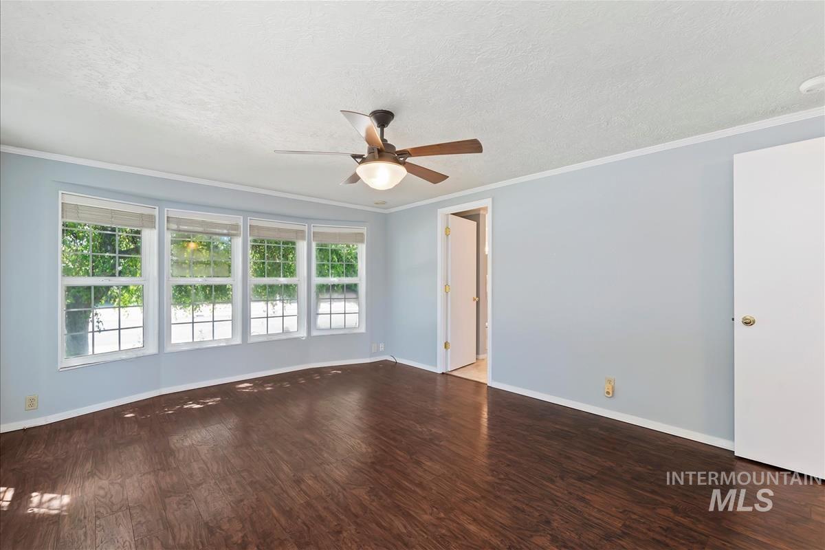 Unfurnished room with a ceiling fan, wood finished floors, a textured ceiling, and crown molding