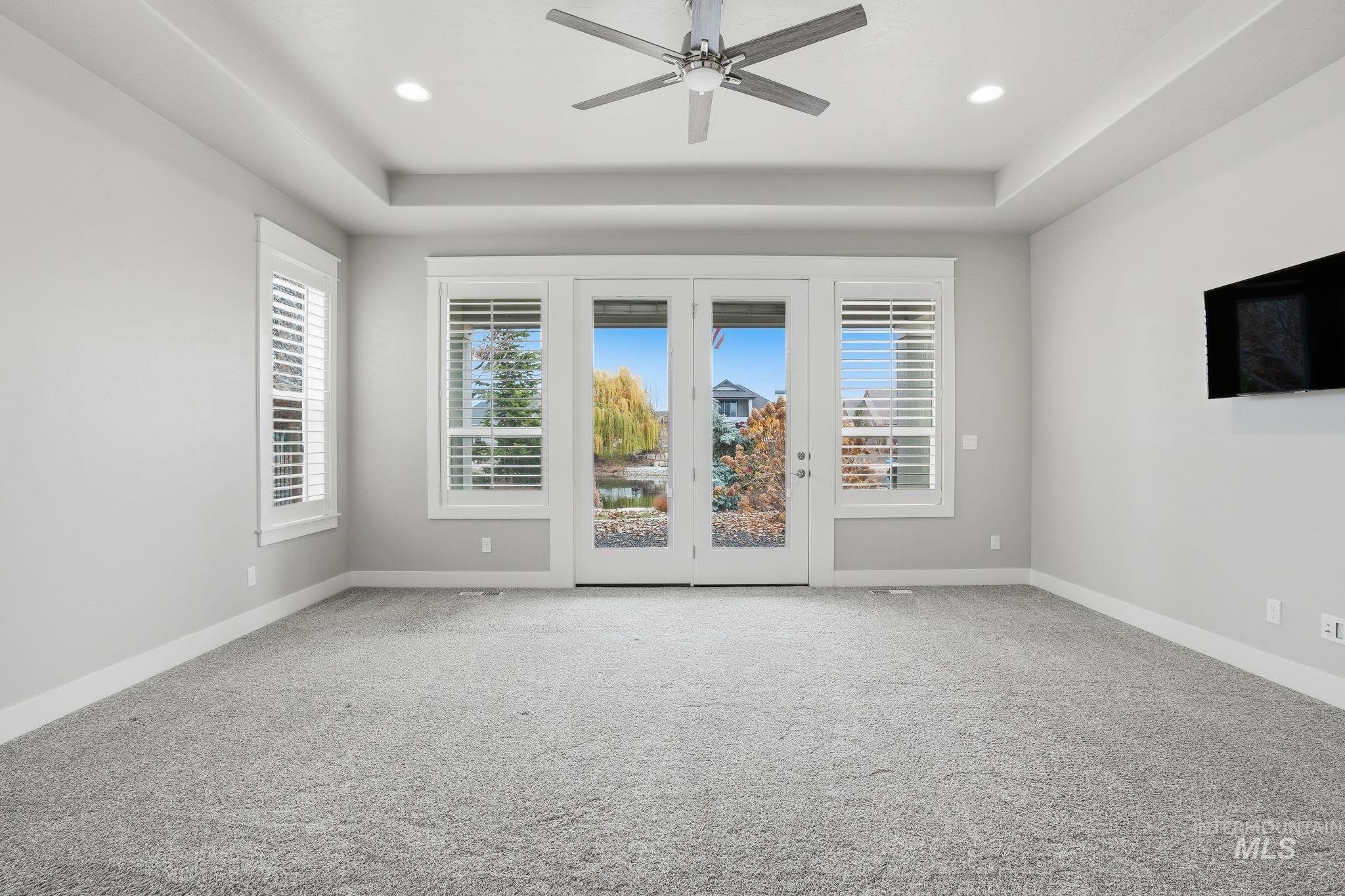 Empty room with carpet floors, a ceiling fan, a raised ceiling, and recessed lighting
