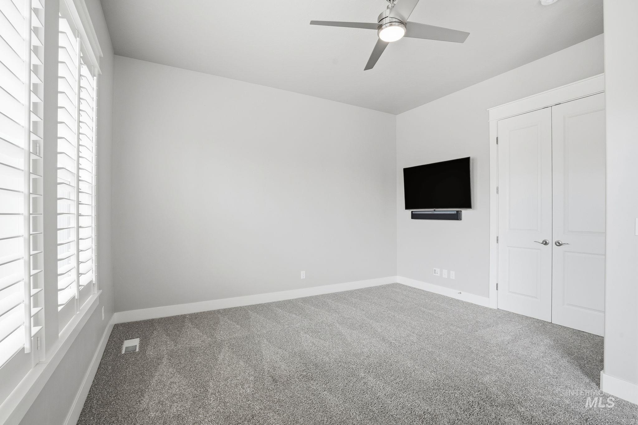 Unfurnished bedroom featuring carpet floors, ceiling fan, and a closet