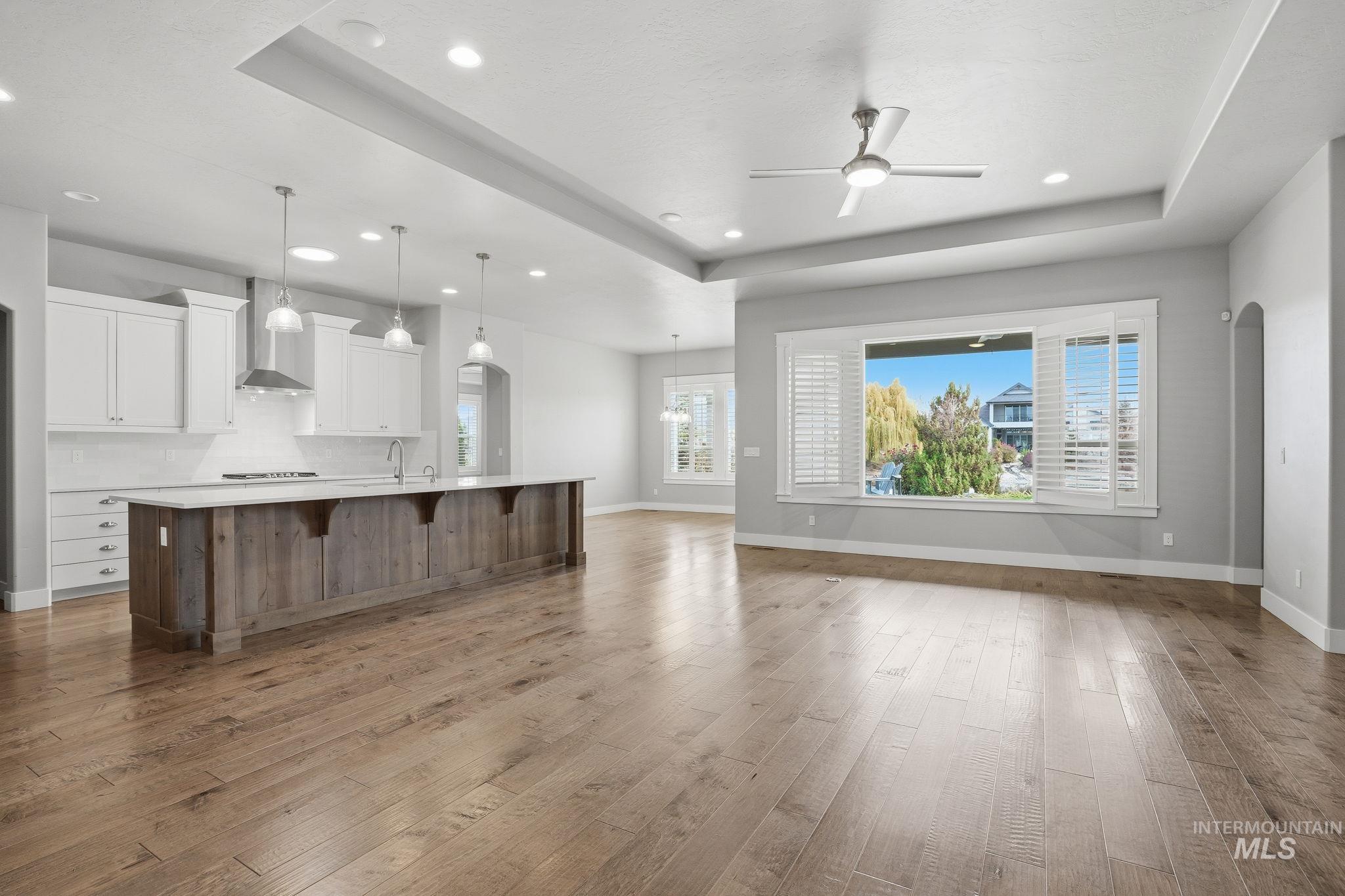 Kitchen with white cabinets, a tray ceiling, open floor plan, and recessed lighting