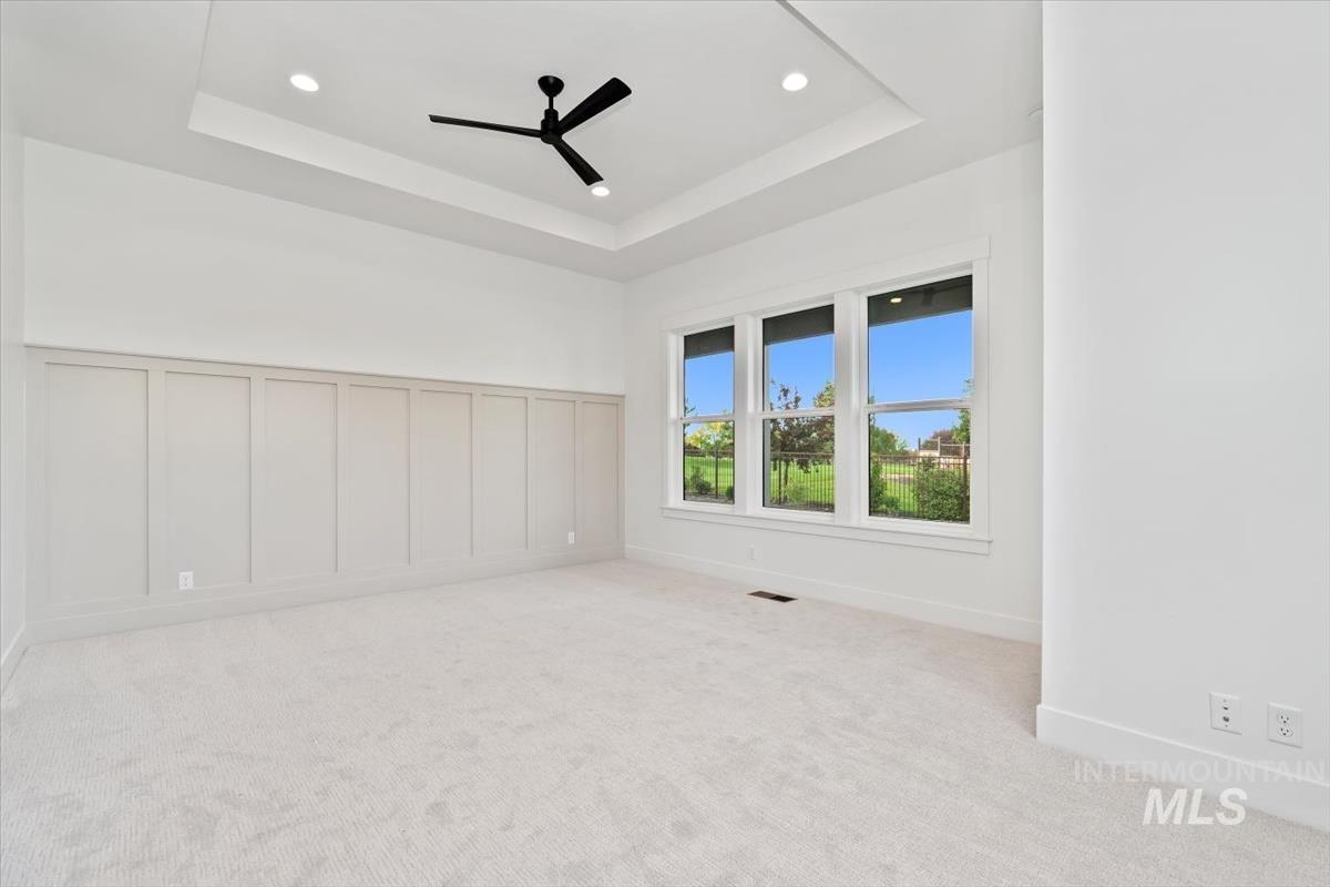 Unfurnished room featuring light colored carpet, a tray ceiling, a decorative wall, recessed lighting, and ceiling fan