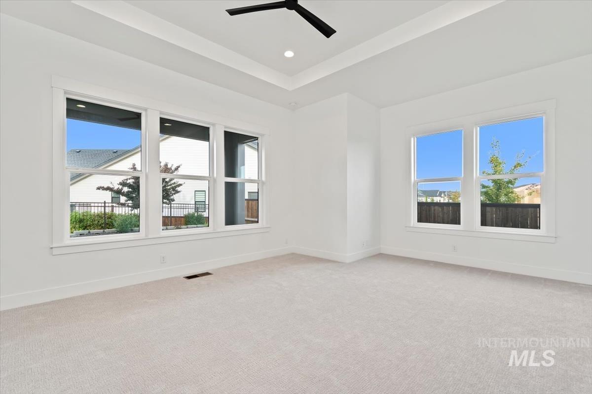 Empty room with light colored carpet, a raised ceiling, and recessed lighting