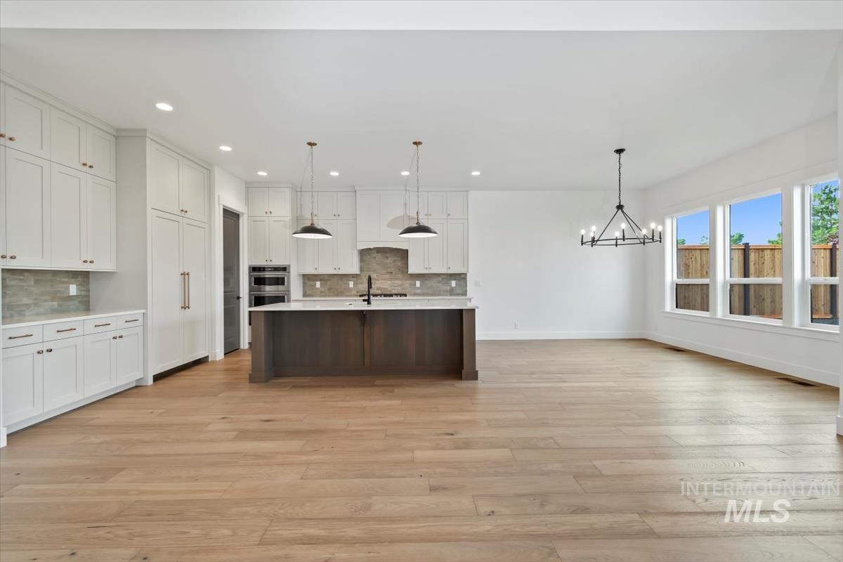 Kitchen featuring pendant lighting, a center island with sink, white cabinetry, recessed lighting, and open floor plan