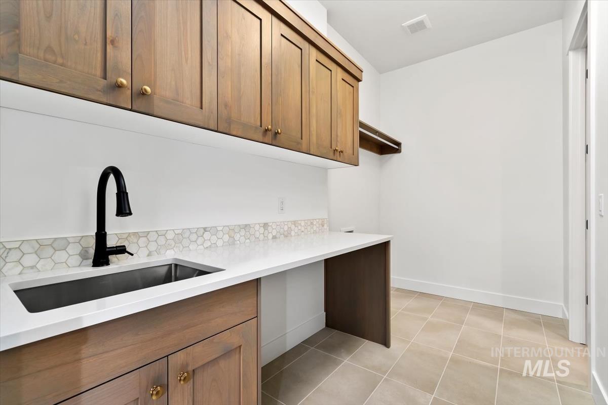 Laundry room with a sink and light tile patterned floors
