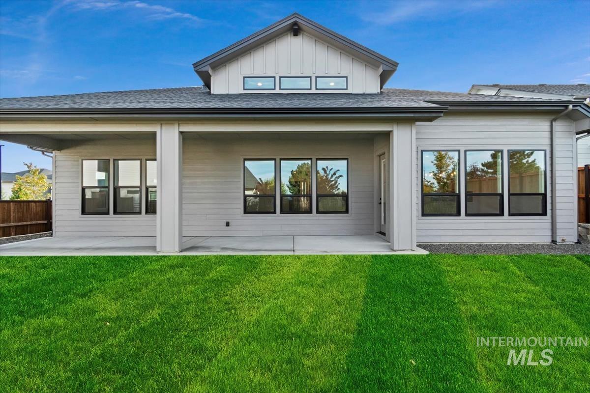 Rear view of property with a patio, board and batten siding, and roof with shingles
