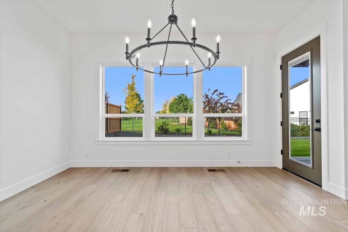 Unfurnished dining area featuring plenty of natural light, light wood-style flooring, and a chandelier