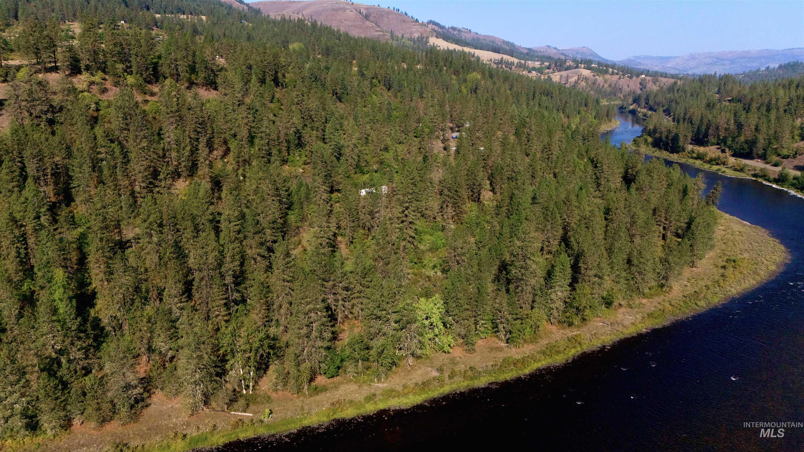 Aerial view of property's location featuring a water and mountain view and a heavily wooded area