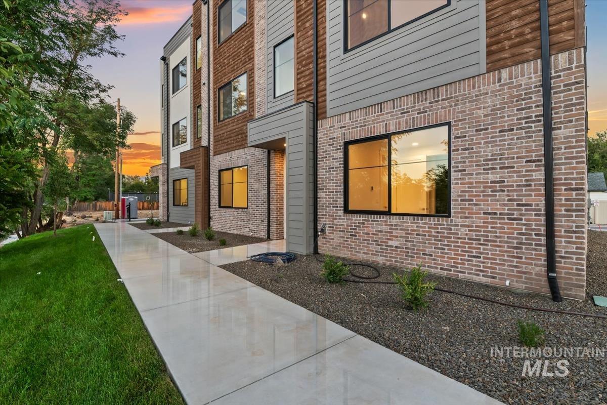 Doorway to property featuring a lawn and brick siding