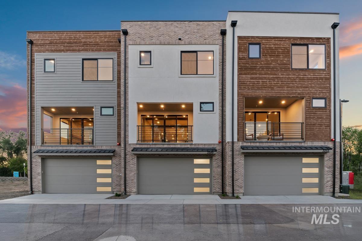 Back of house with a balcony, a garage, and driveway