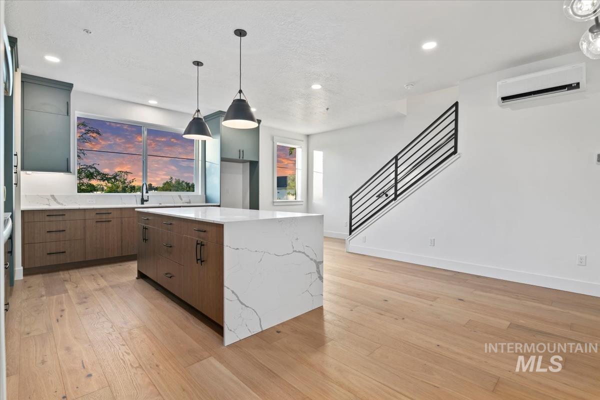 Kitchen with hanging light fixtures, light wood-style flooring, a center island, a wall mounted AC, and recessed lighting