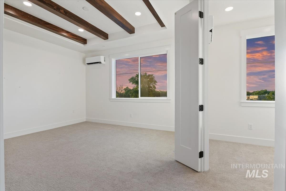 Empty room with beam ceiling, light colored carpet, recessed lighting, and a wall mounted AC