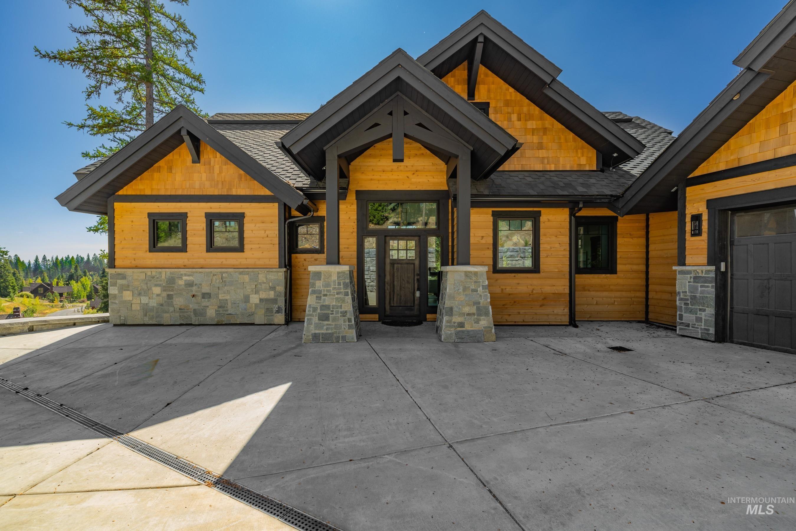 Craftsman house with stone siding, a shingled roof, and an attached garage