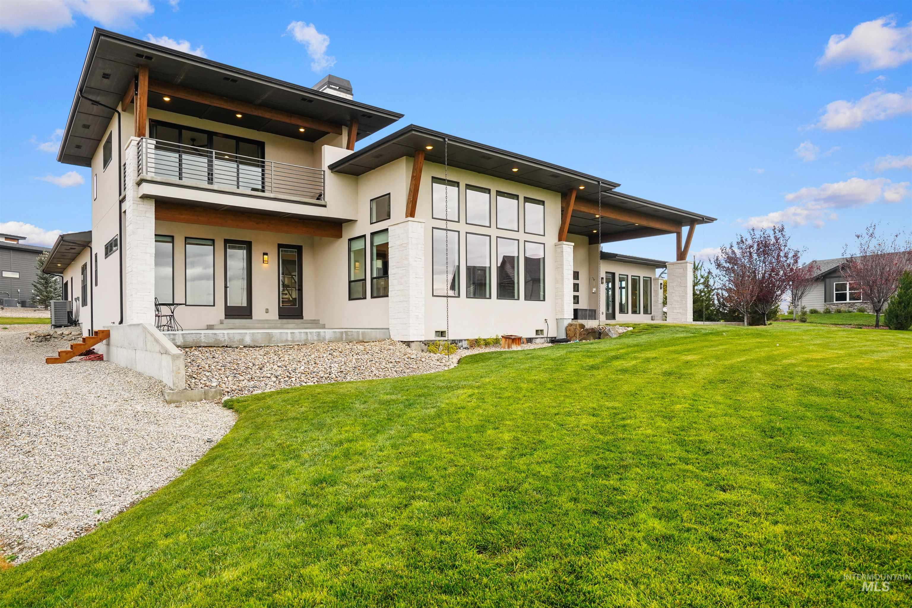 Rear view of house featuring a lawn, stucco siding, a patio, a balcony, and a chimney