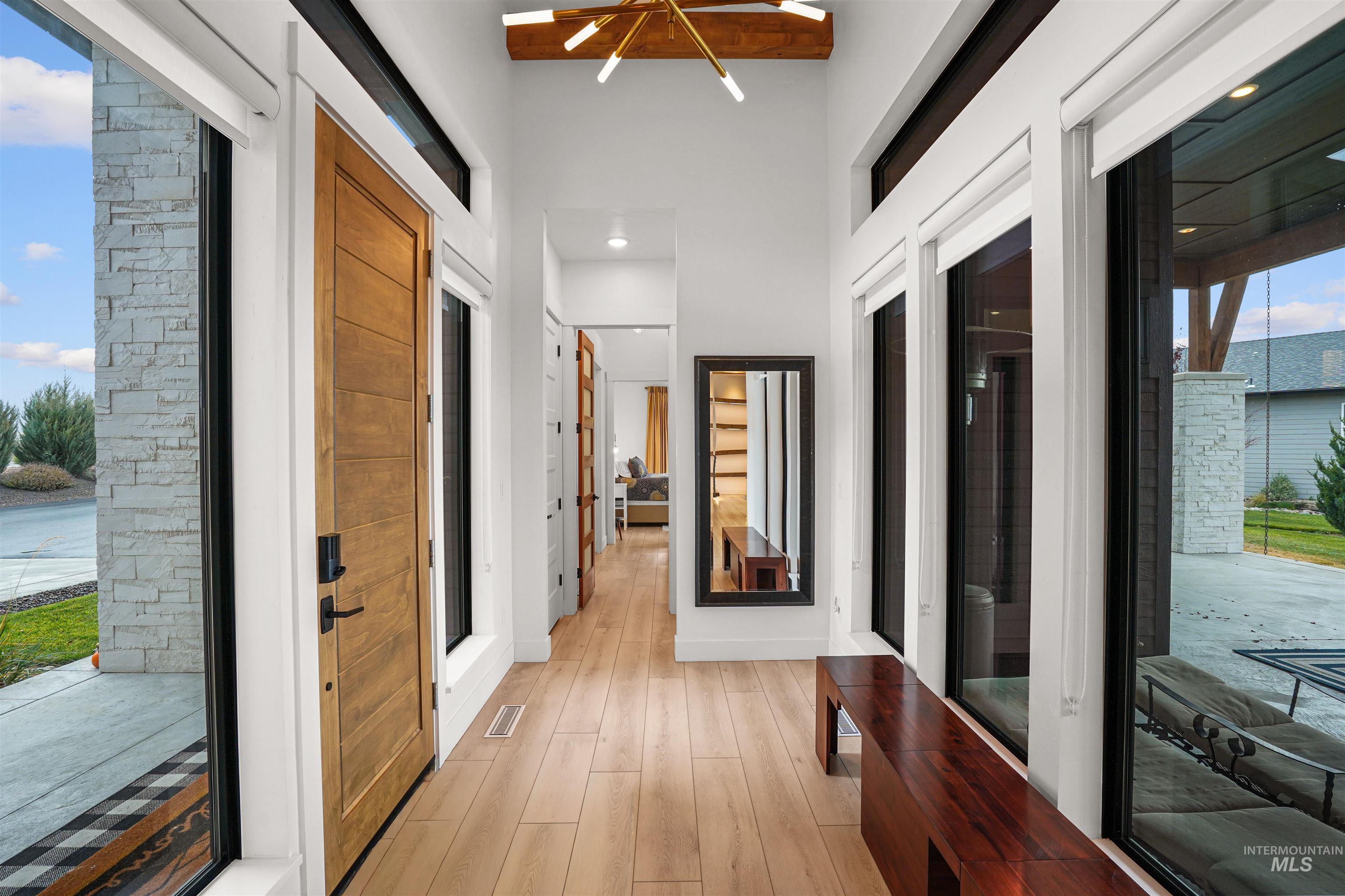 Hall featuring light wood-type flooring, a chandelier, and a towering ceiling