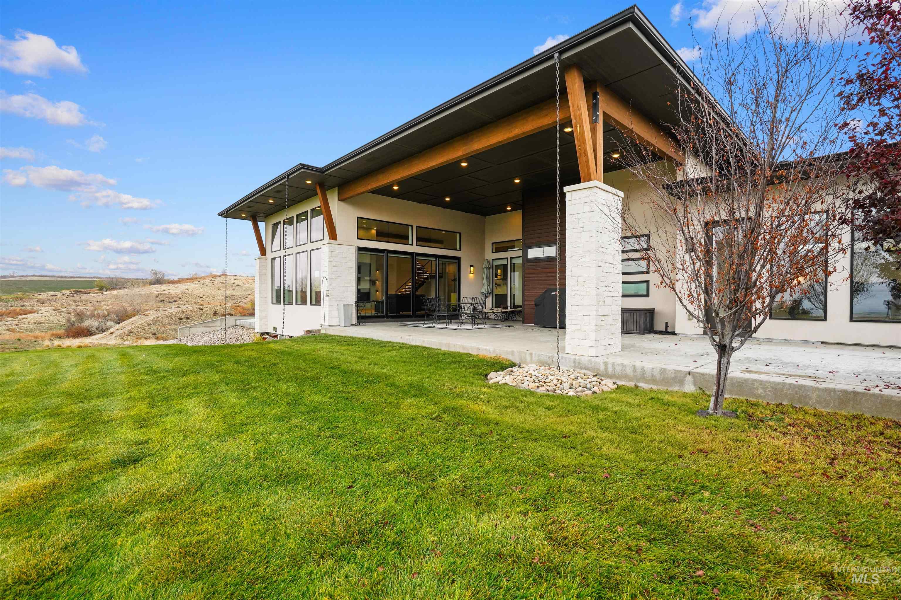 Rear view of house with a patio, a yard, and stucco siding