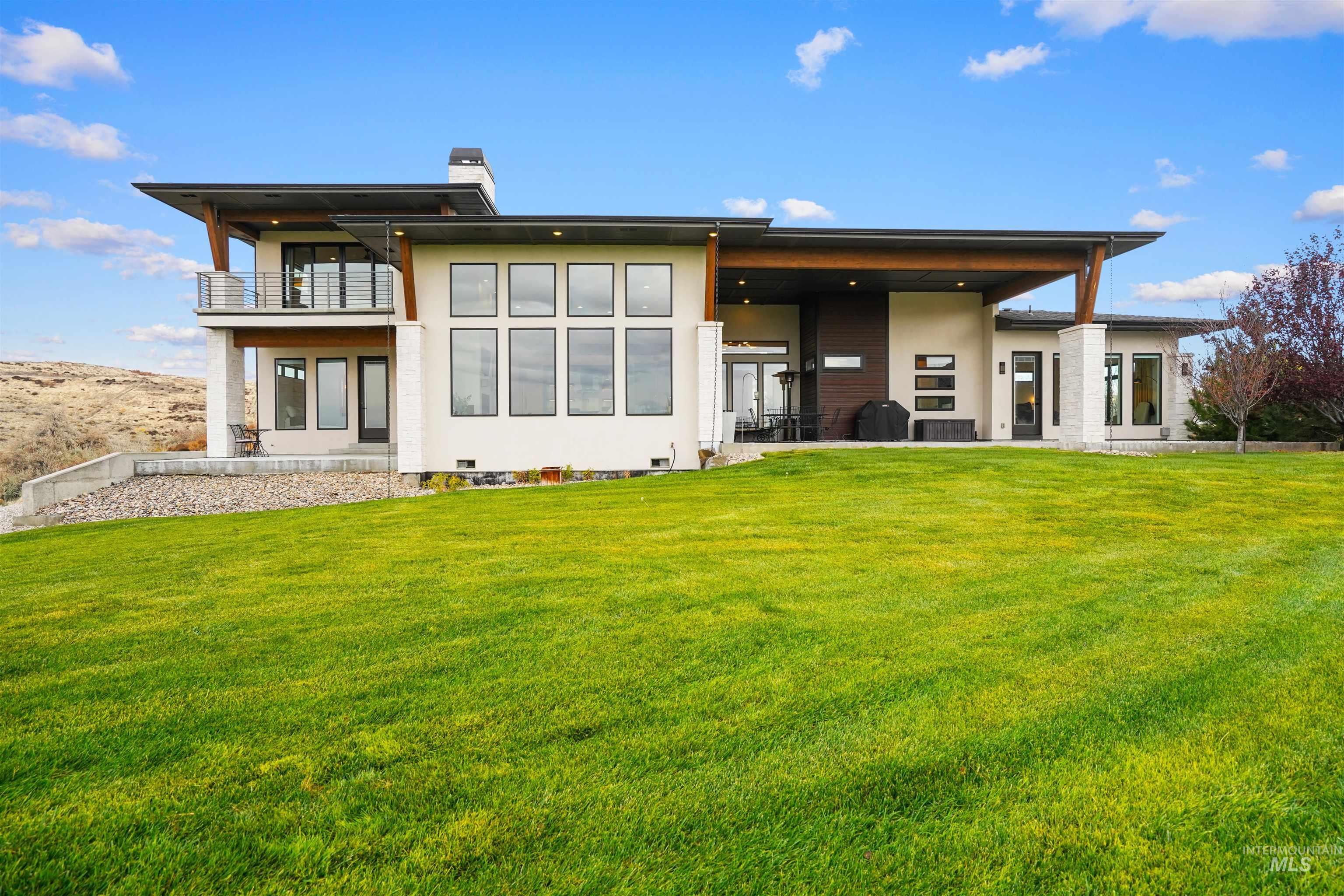 Rear view of house featuring a yard, a chimney, a patio, and stucco siding
