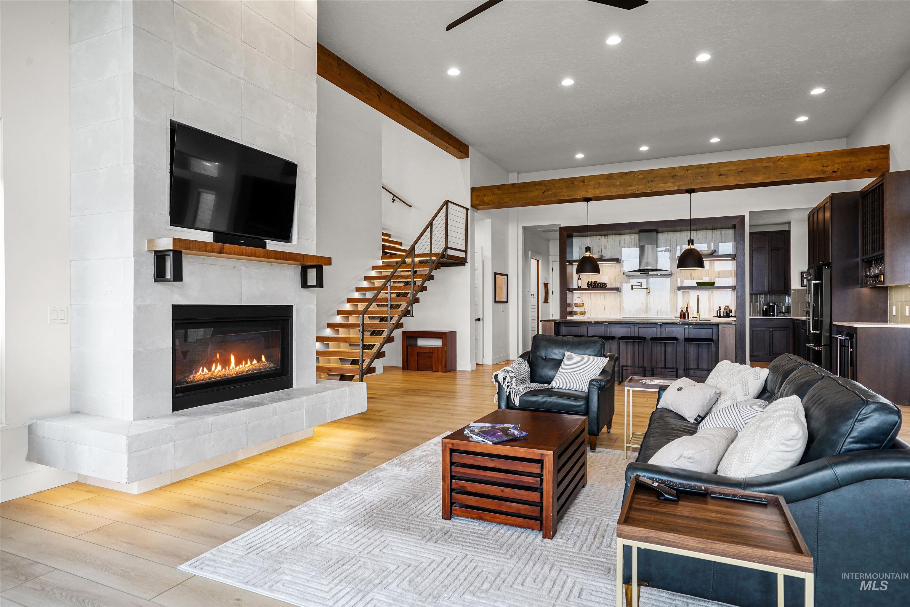 Living area featuring recessed lighting, a tile fireplace, light wood-type flooring, stairway, and ceiling fan