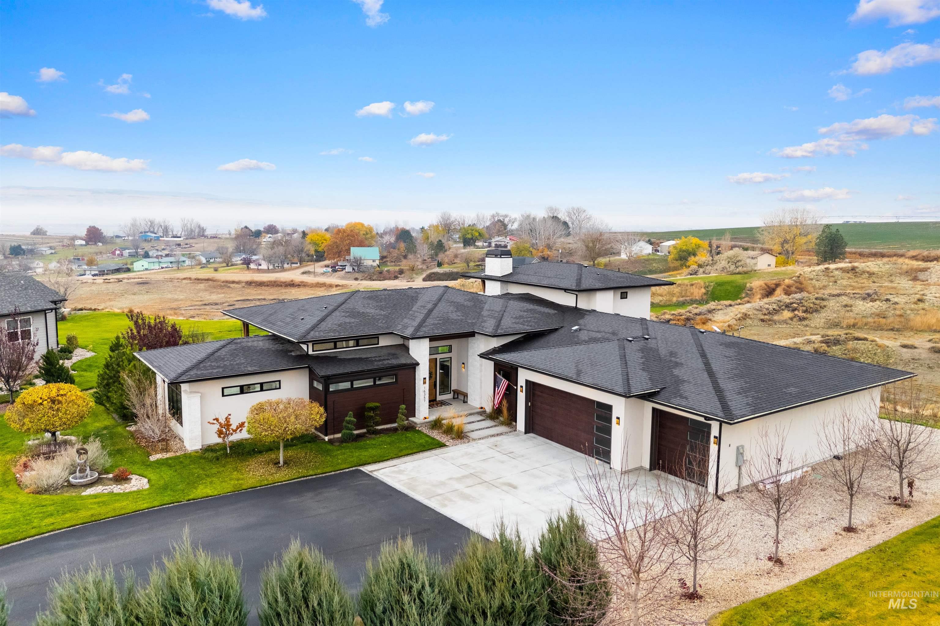 View of front of house featuring an attached garage, driveway, a front yard, and stucco siding