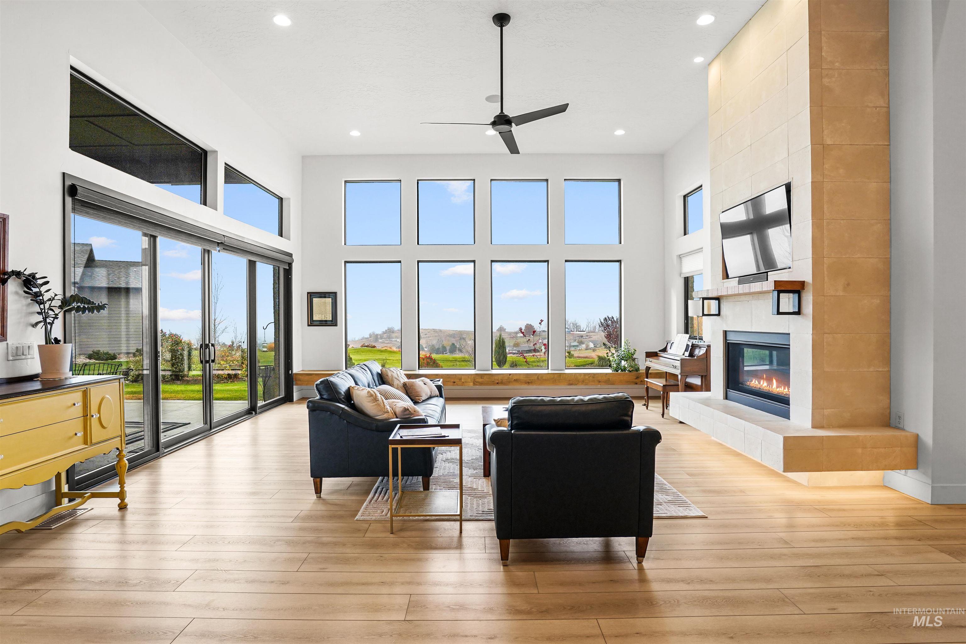 Living room featuring a fireplace, plenty of natural light, recessed lighting, a towering ceiling, and light wood-type flooring