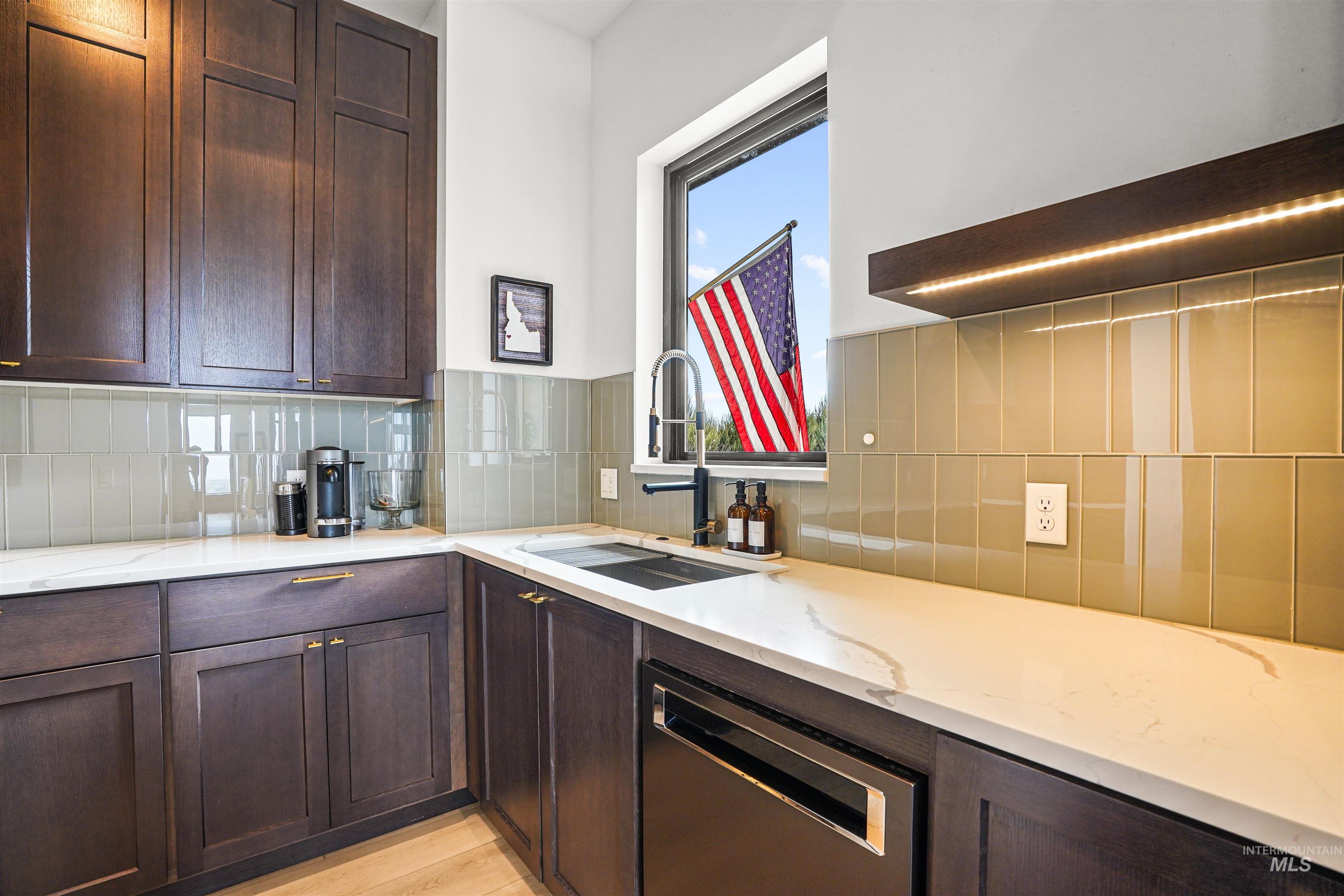 Kitchen with dark brown cabinetry and light stone countertops