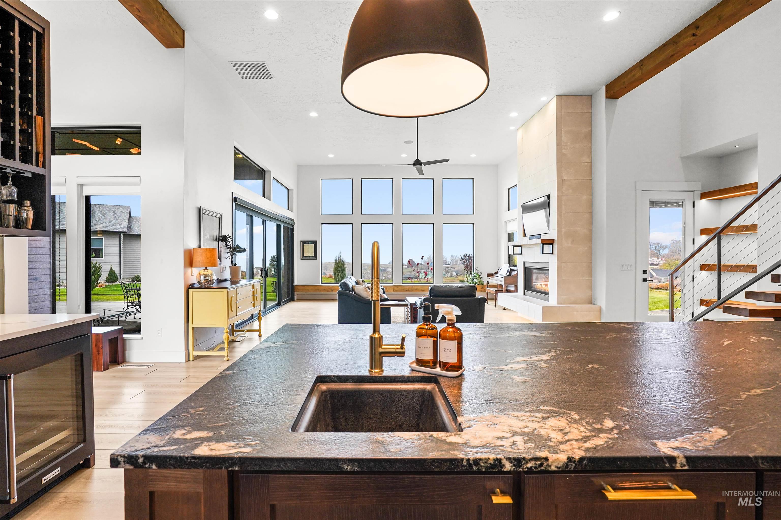 Kitchen featuring dark stone countertops, a fireplace, plenty of natural light, beverage cooler, and a towering ceiling