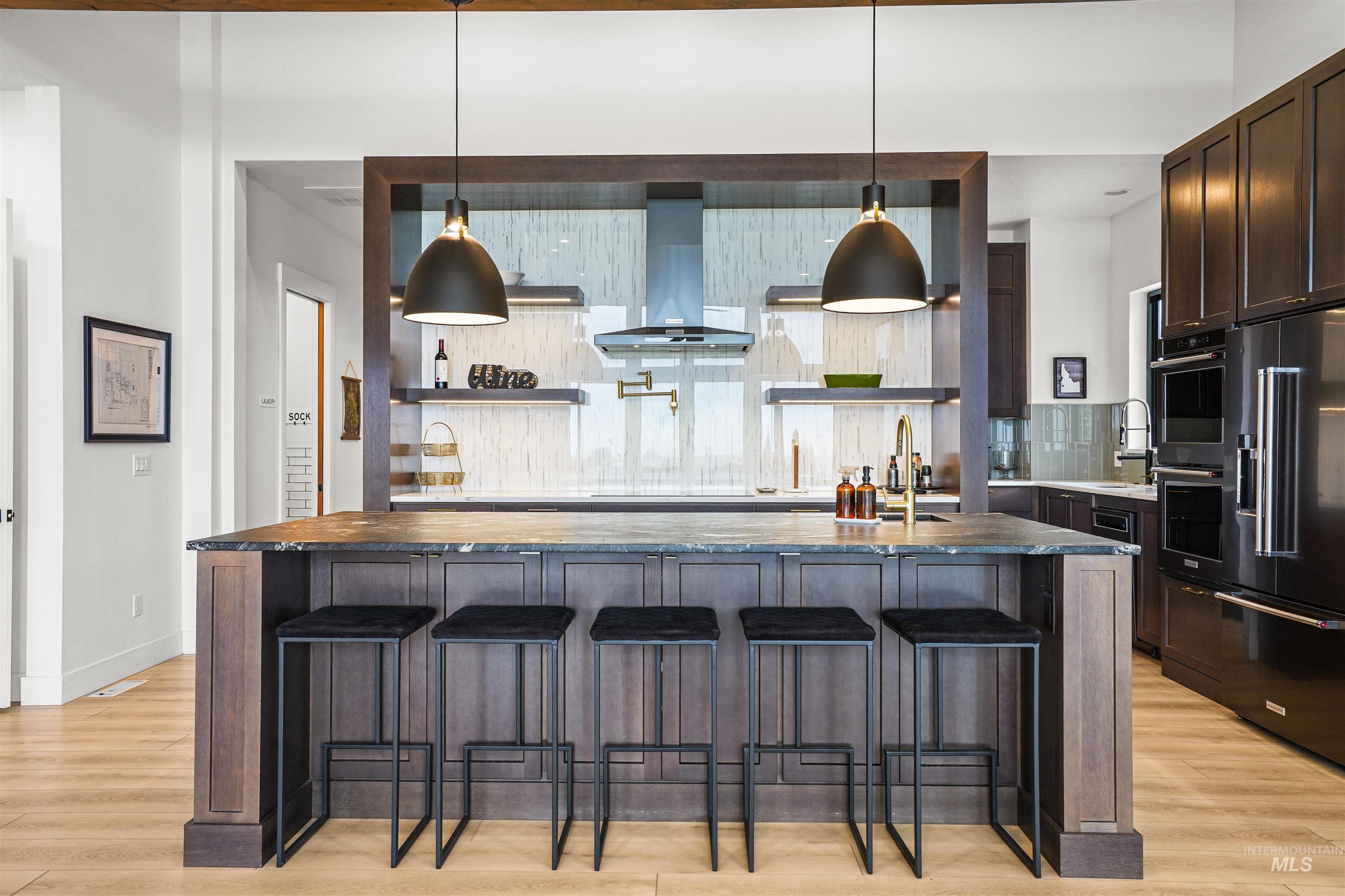 Kitchen featuring backsplash, a large island, a kitchen bar, wood counters, and dark brown cabinets