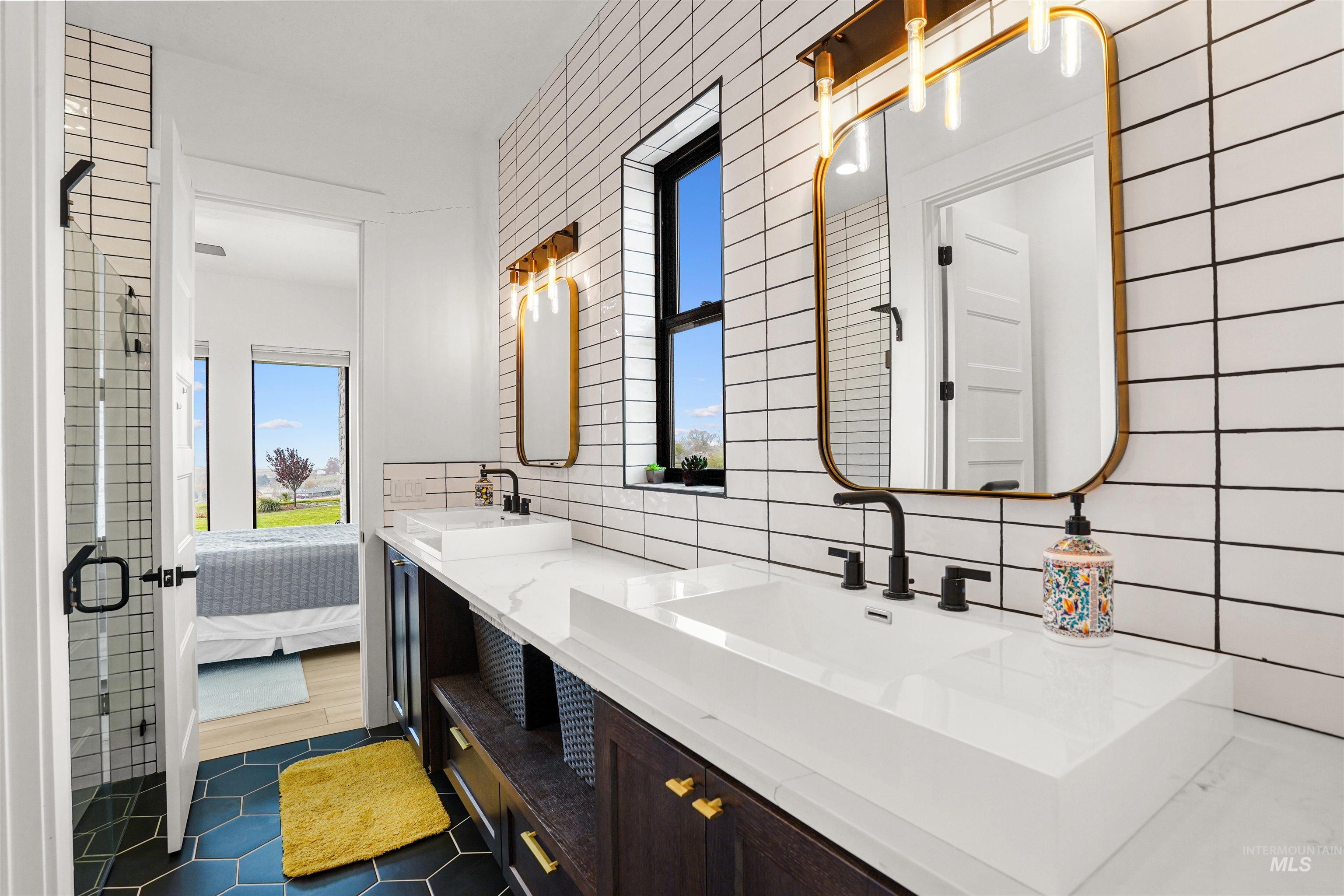 Full bathroom featuring ensuite bath, double vanity, tasteful backsplash, dark tile patterned flooring, and a shower stall