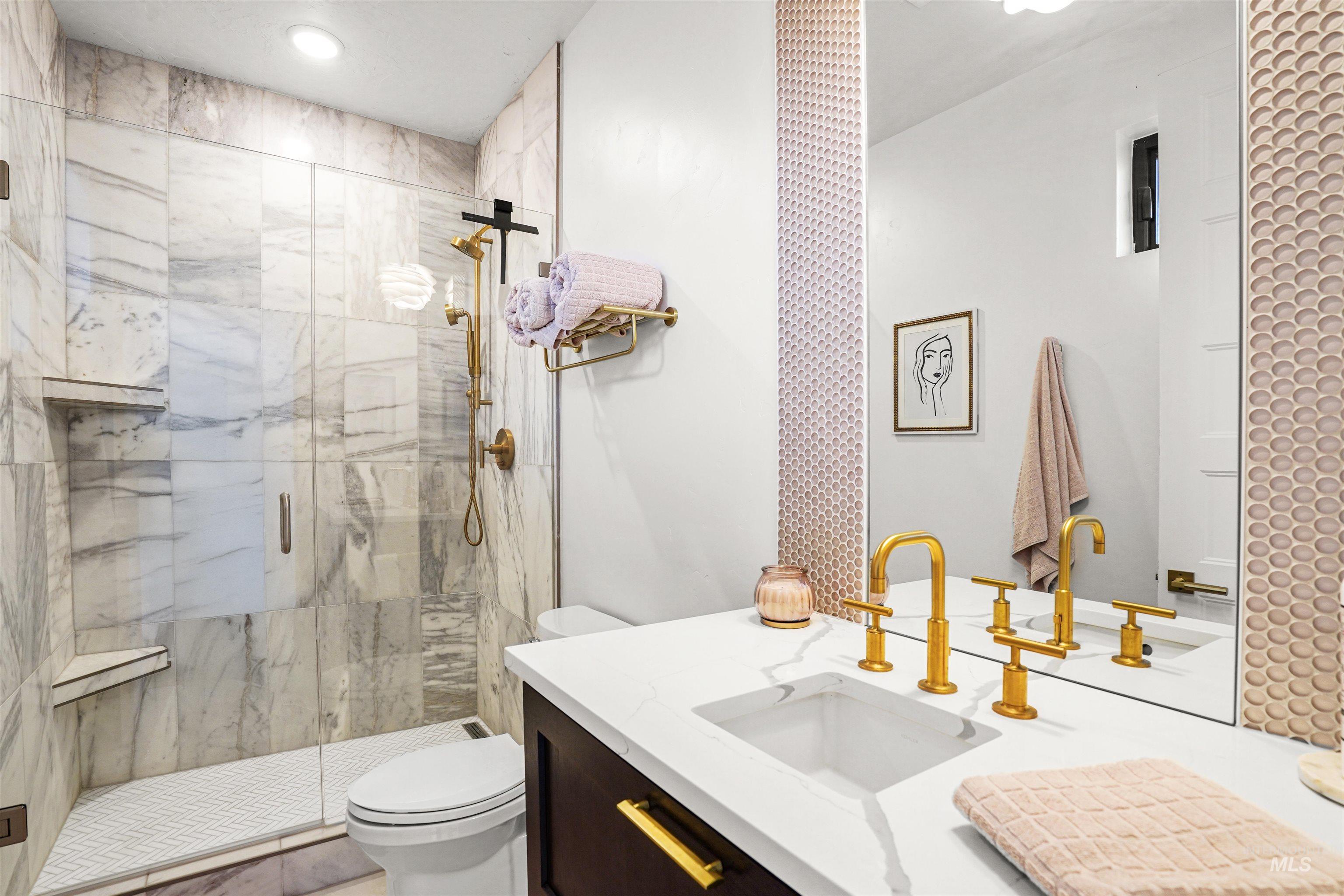 Bathroom featuring a marble finish shower and vanity