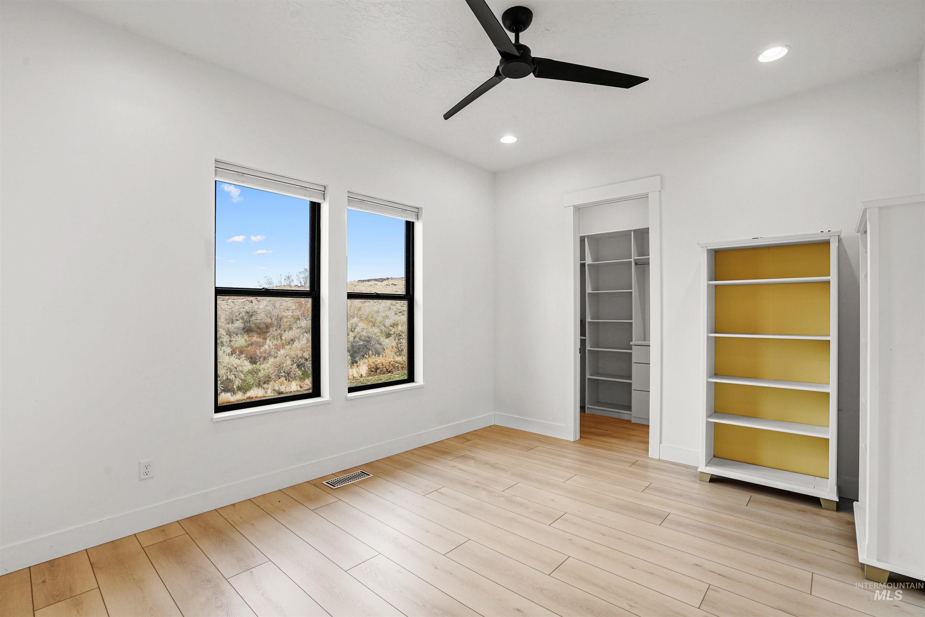 Unfurnished bedroom with a spacious closet, ceiling fan, light wood-style floors, and recessed lighting