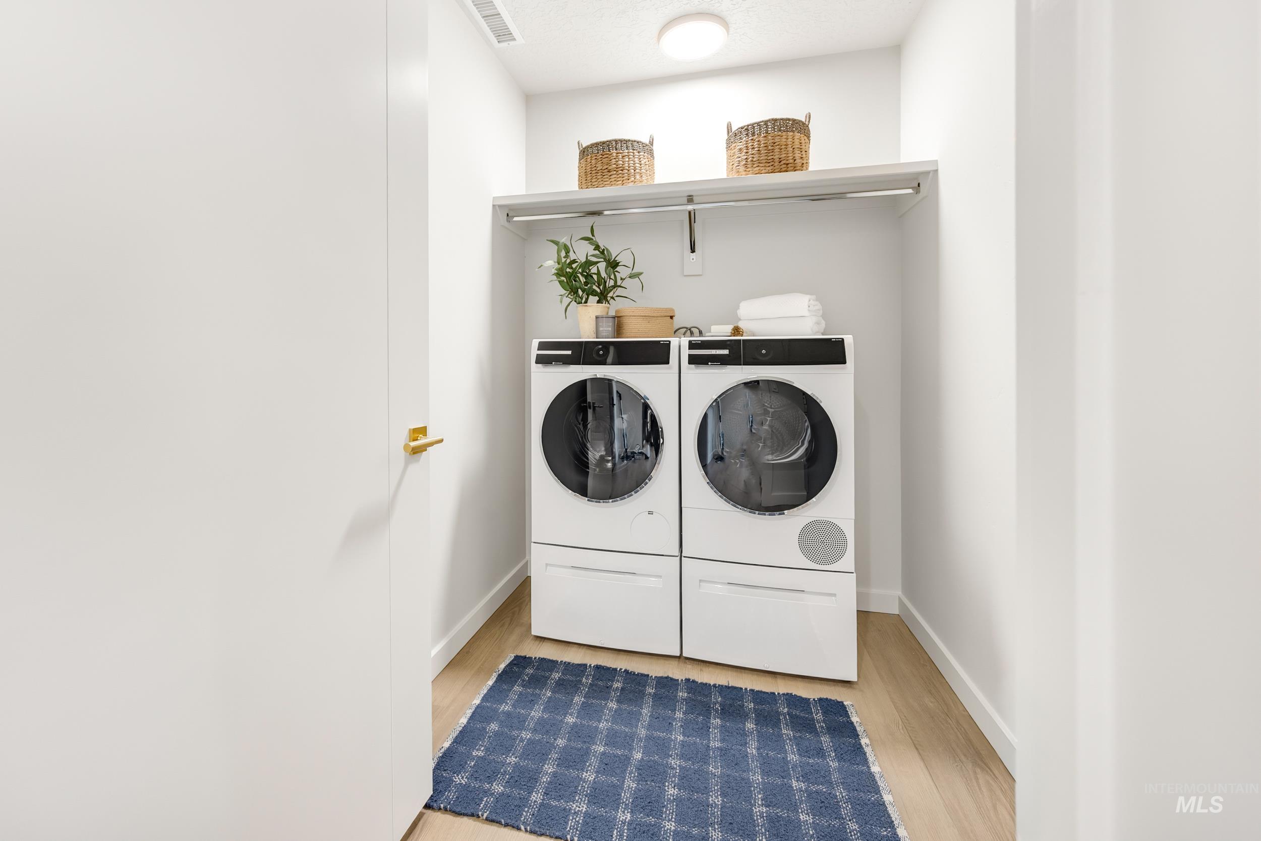 Laundry area with light wood-style flooring and washer and dryer