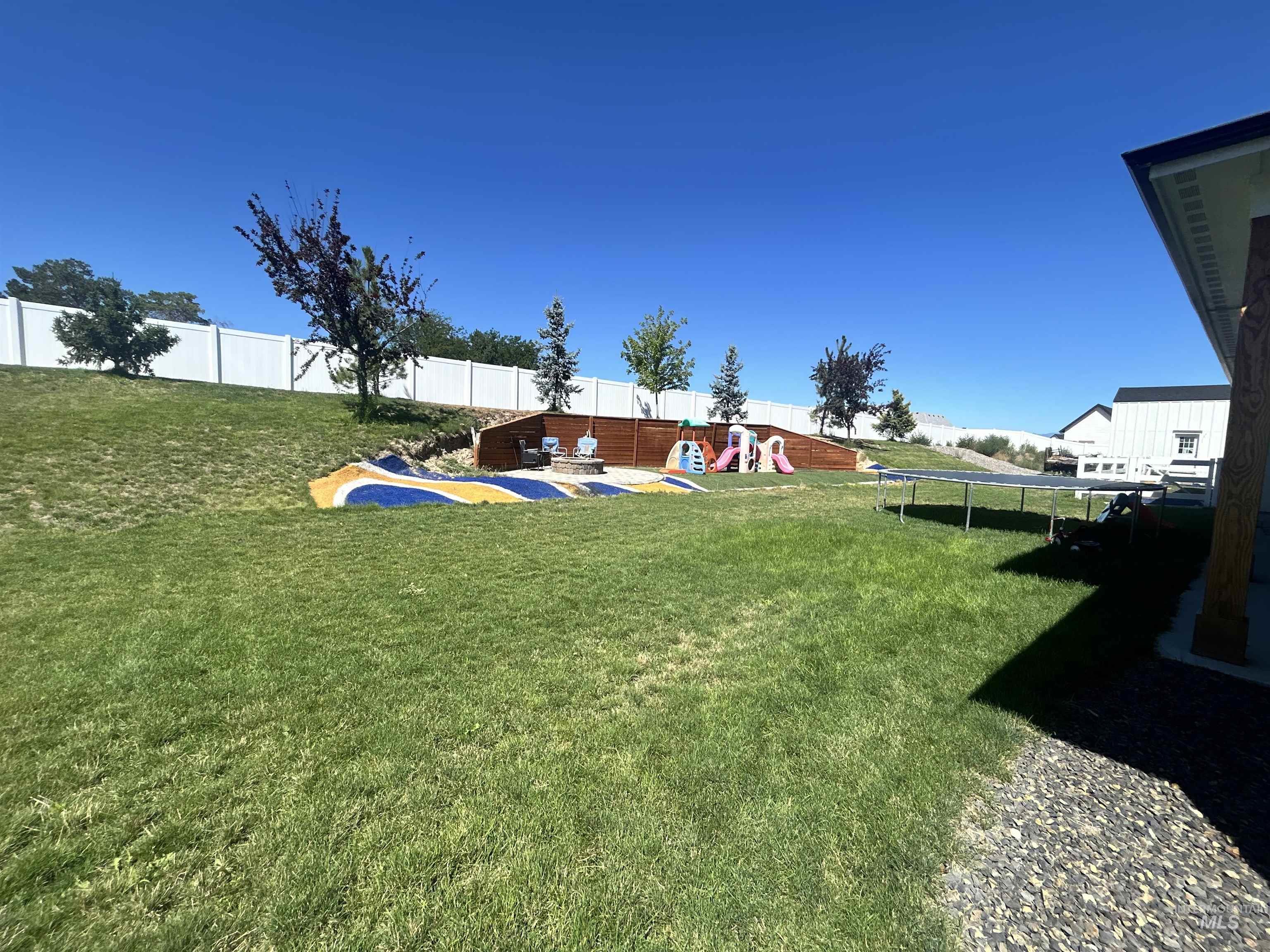 Fenced backyard with a trampoline and a playground