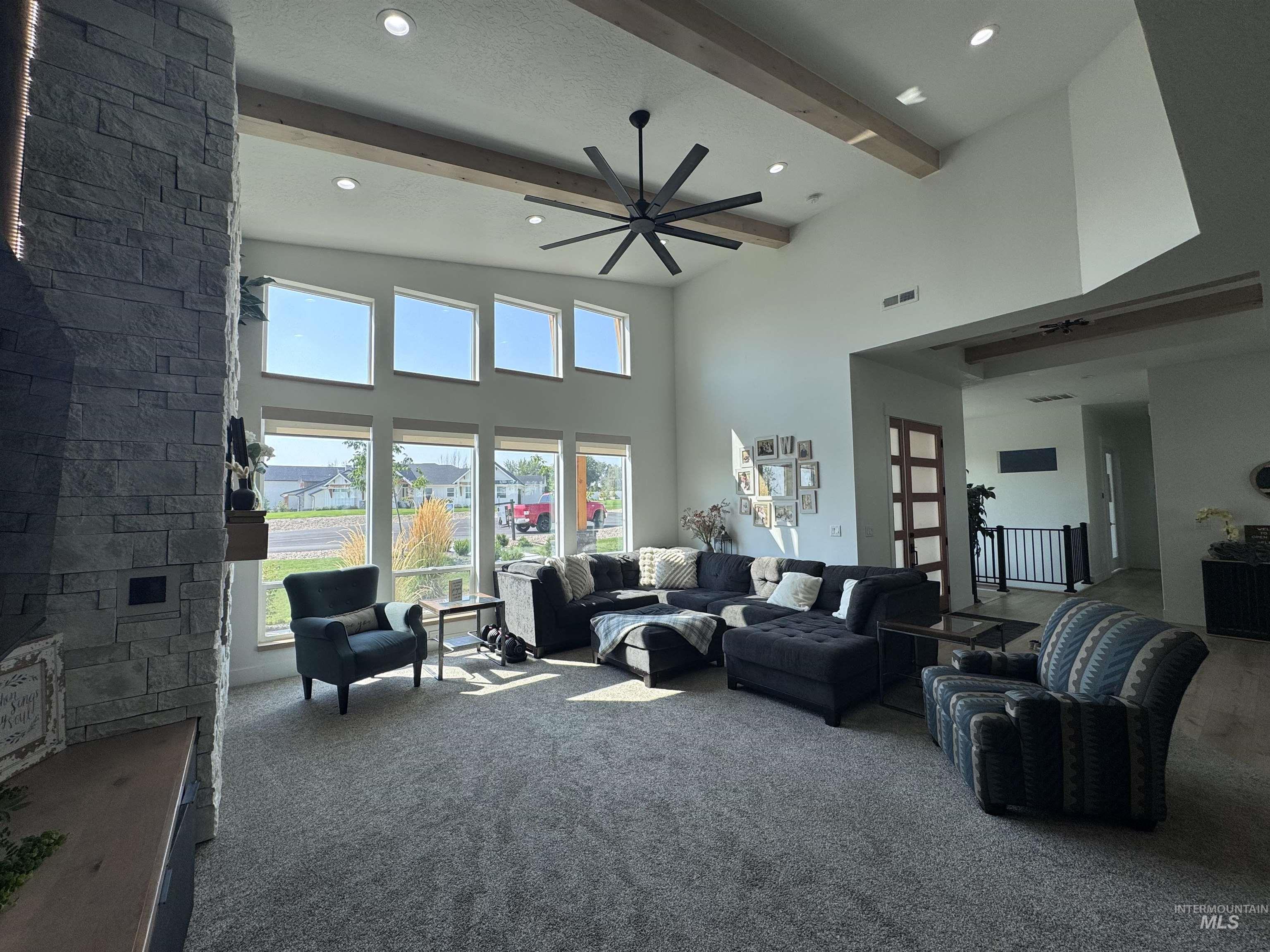 Carpeted living area featuring beamed ceiling, a towering ceiling, a ceiling fan, and recessed lighting
