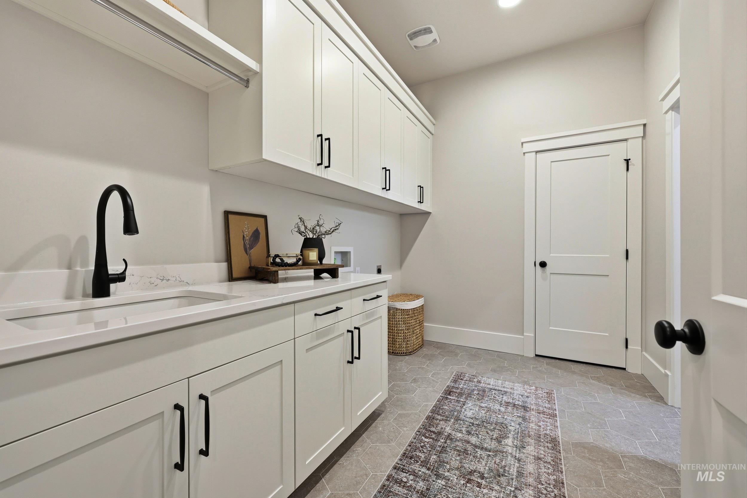 Laundry room featuring cabinet space, hookup for a washing machine, hookup for an electric dryer, recessed lighting, and light stone finish floors