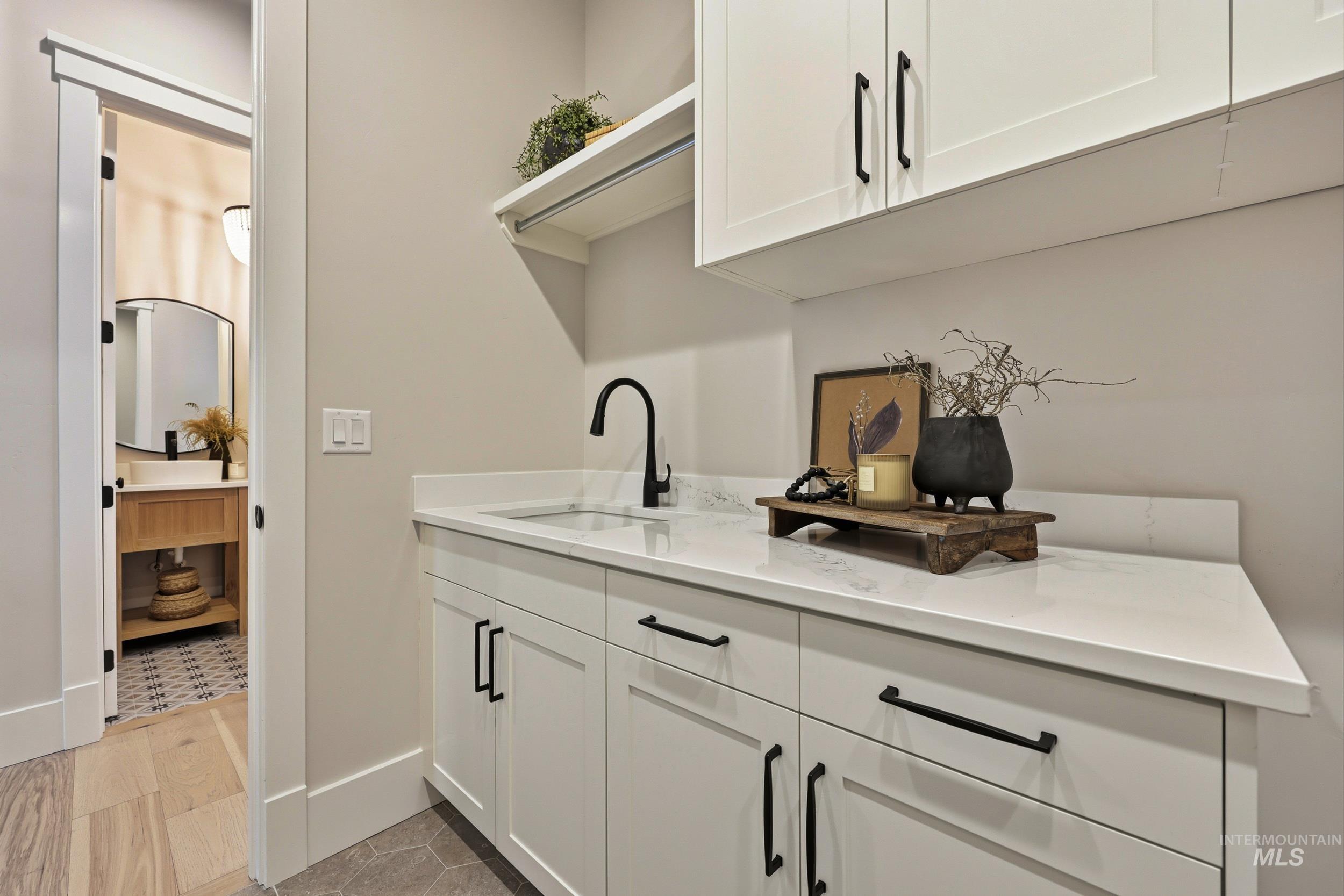 Bar area featuring white cabinets, light stone counters, open shelves, and light tile patterned flooring
