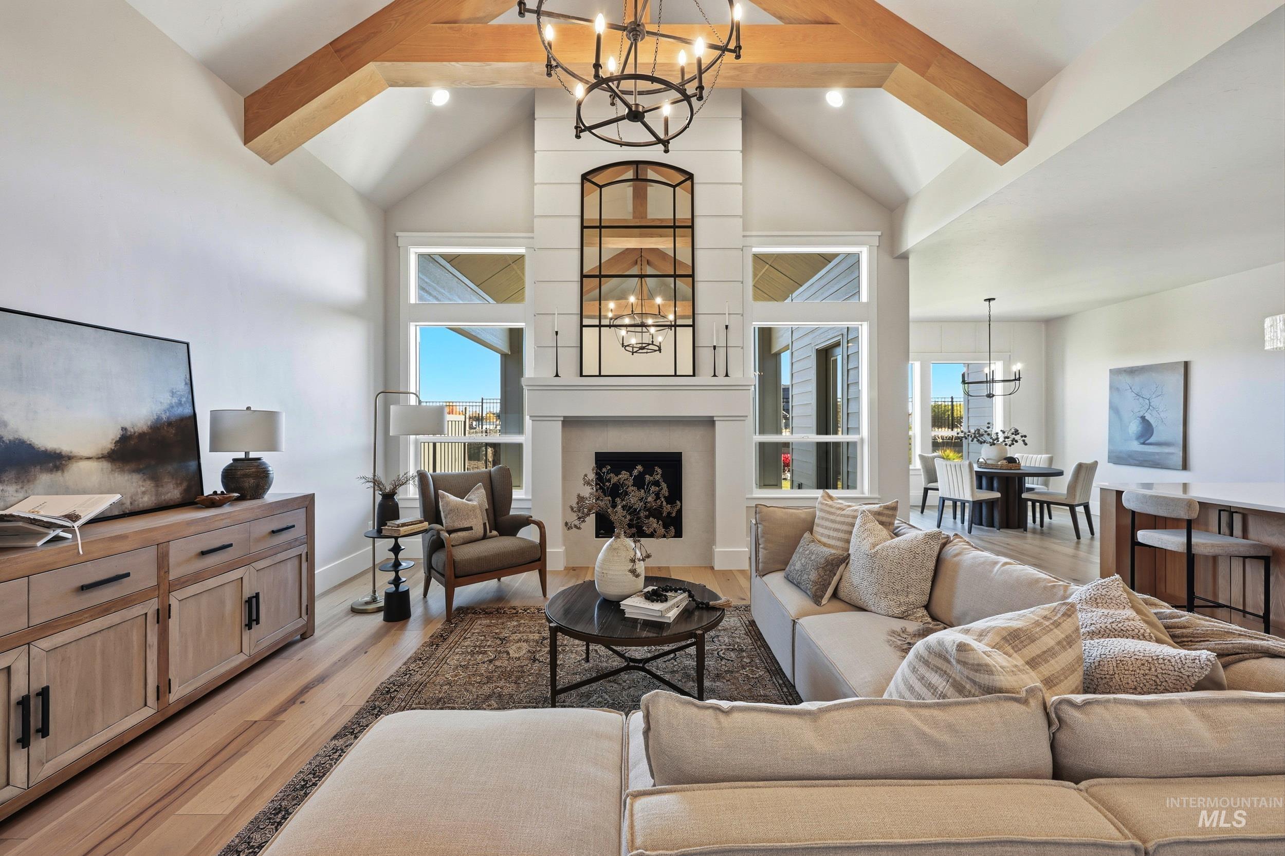 Living room featuring a chandelier, beamed ceiling, light wood-type flooring, a fireplace, and high vaulted ceiling