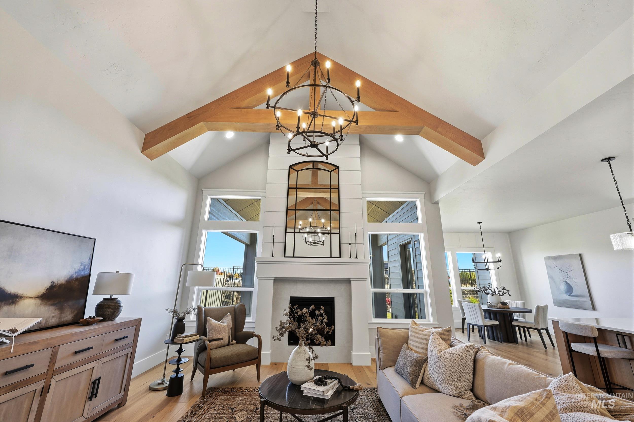 Living room with a chandelier, light wood-style flooring, beamed ceiling, plenty of natural light, and a fireplace