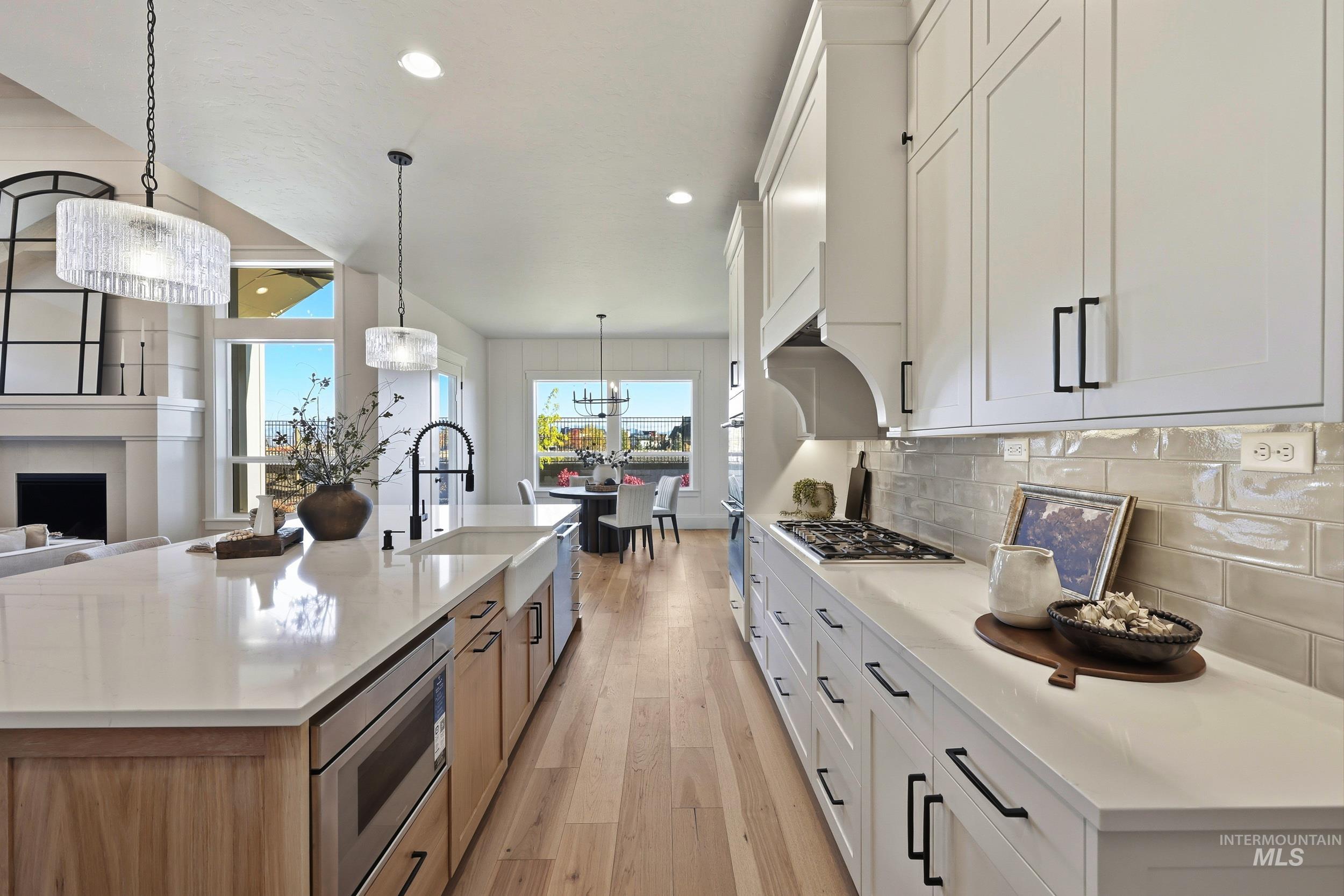 Kitchen with white cabinets, recessed lighting, light wood-type flooring, pendant lighting, and a large island with sink