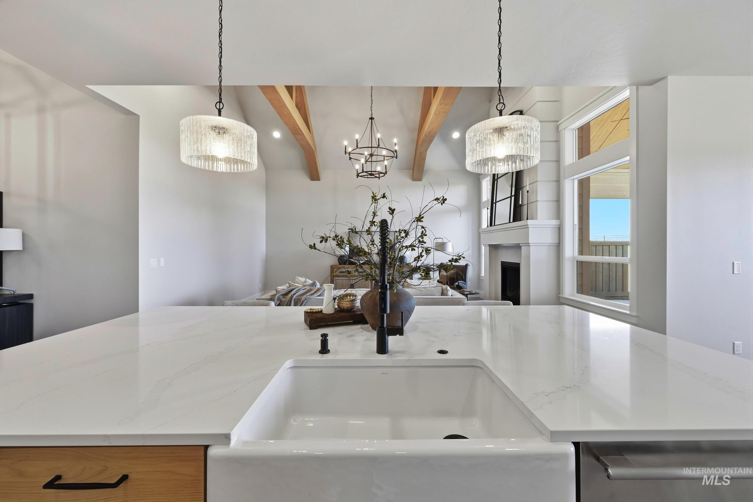 Kitchen with beamed ceiling, a fireplace, light stone countertops, decorative light fixtures, and dishwasher