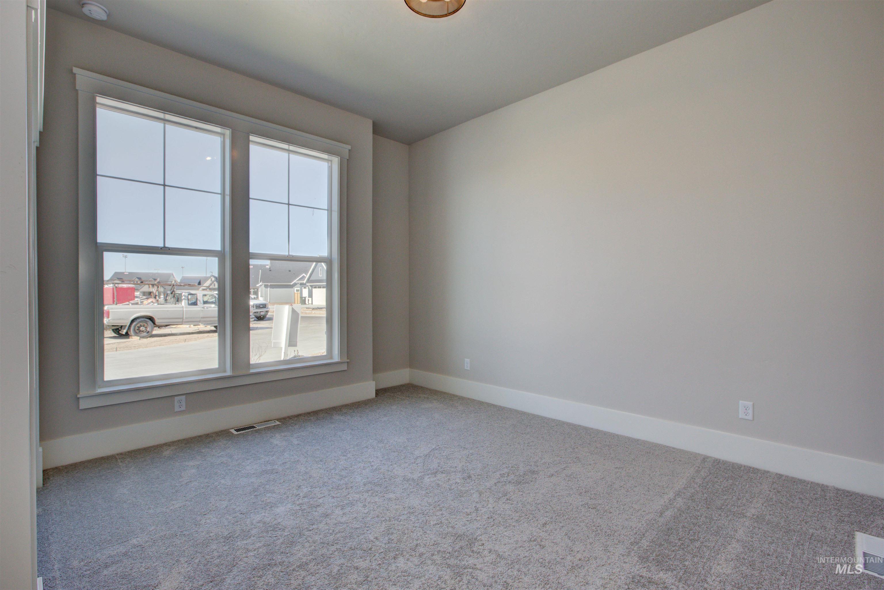 Carpeted spare room featuring baseboards